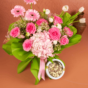 Bouquet of pink flowers with a small container of chocolates on a brown background